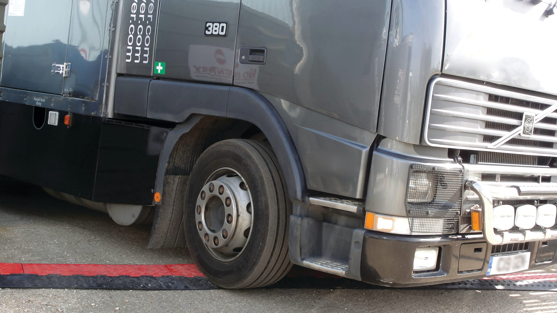 Heavy bus drives over cable protector on ground